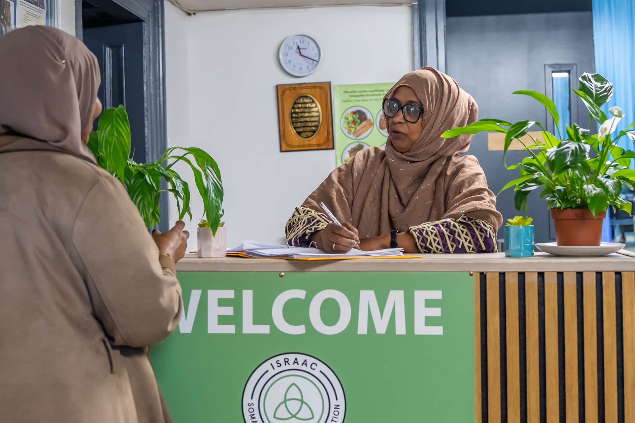 A visitor speaking with a member of the Israac team at reception